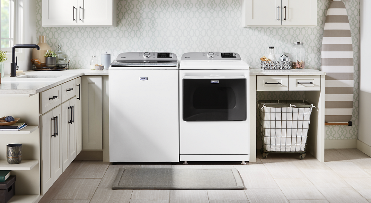 White Maytag® Top load washer and dryer pair in a laundry room with off white cabinetry