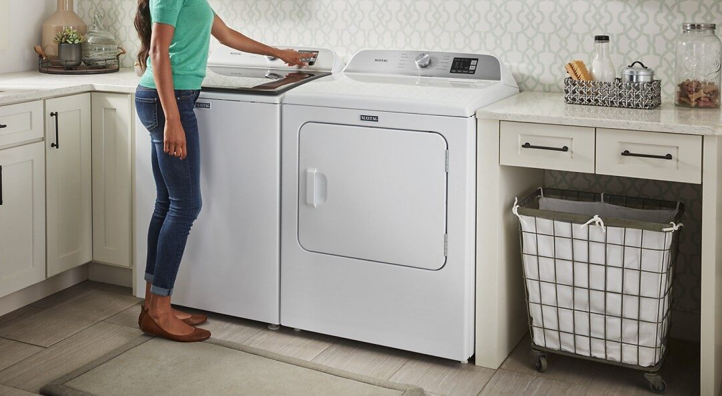 Person selecting settings on a white Maytag® top load washer