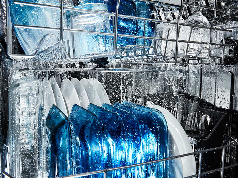 Dishes being rinsed on the top and bottom racks of a dishwasher