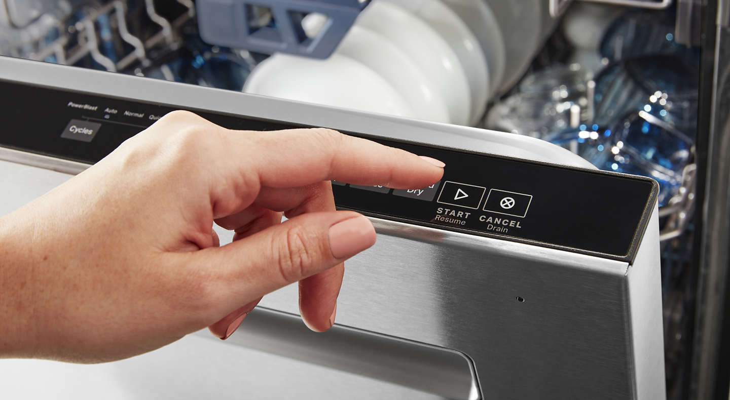 Hand pressing start button Maytag® dishwasher