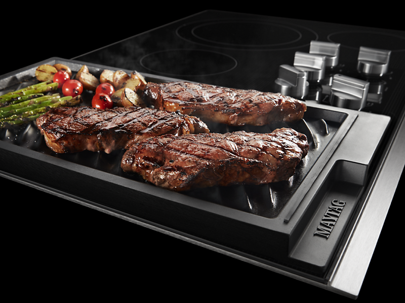 Steak and vegetables cooking on a Maytag® grill pan
