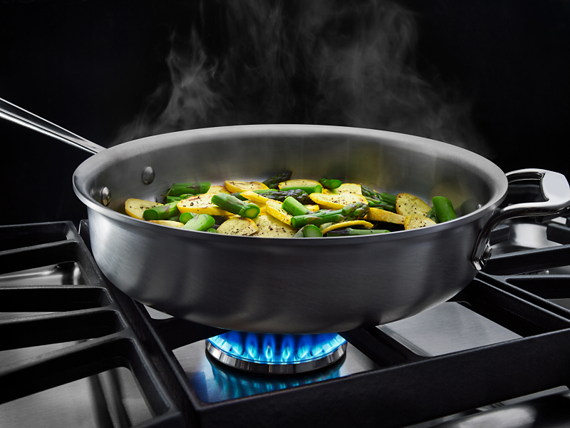 Vegetables cooking in a pan on a gas cooktop