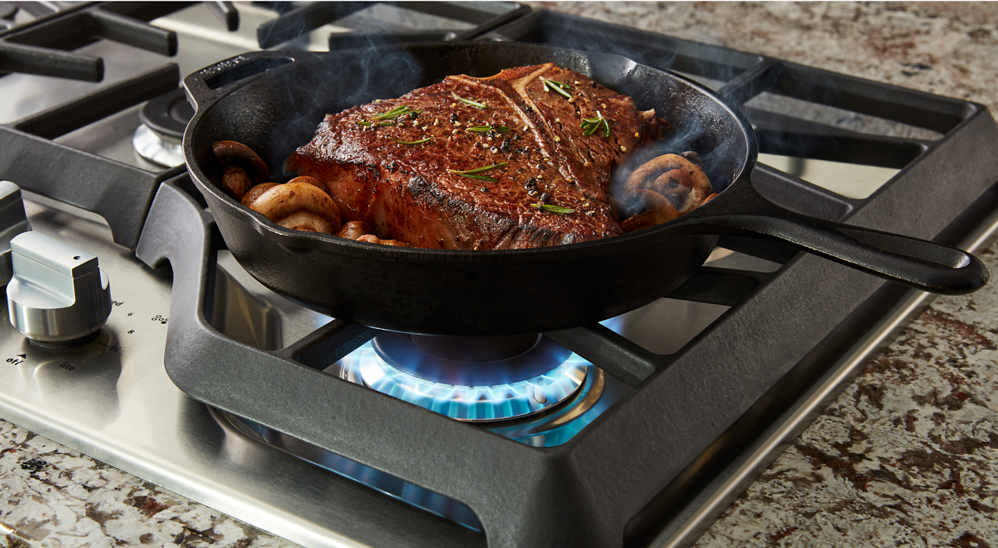 Steak cooking on a gas cooktop