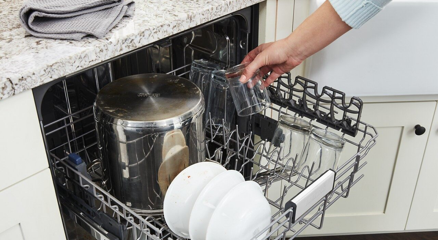 Person putting glasses on top rack of dishwasher