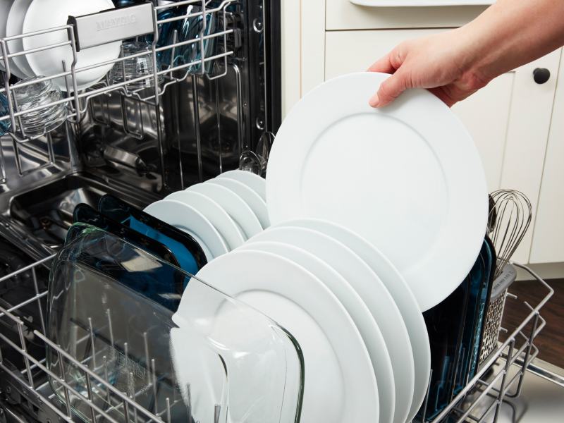Person removing clean plate from a dishwasher.
