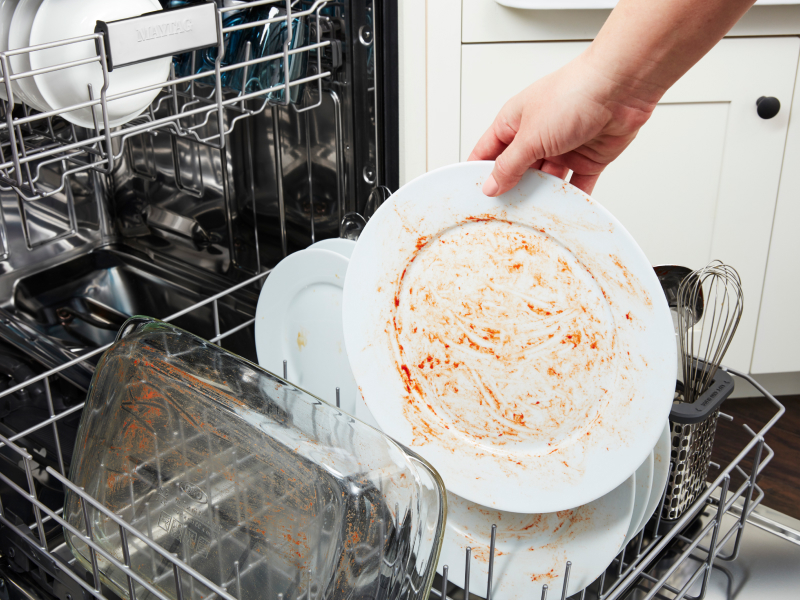 Person placing dirty dishes in a dishwasher.