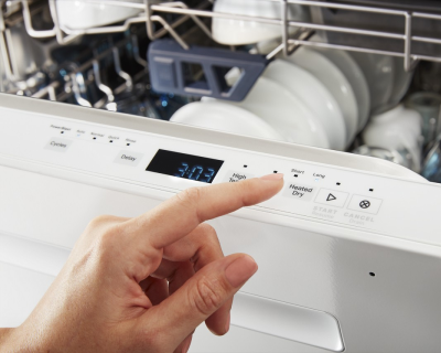 Person selecting dishwasher cycle on control panel