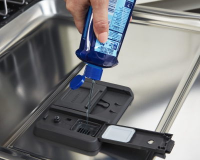 Person dispensing detergent into dishwasher