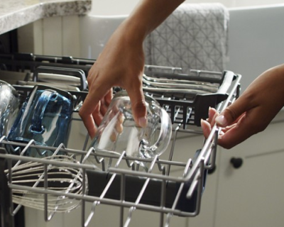 Person placing glass on dishwasher rack