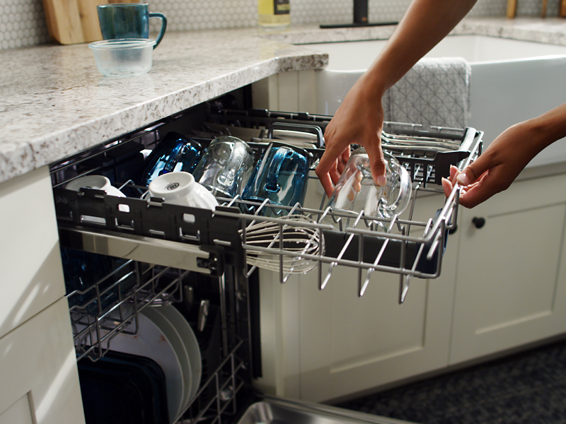 Person loading dishes into a dishwasher top rack