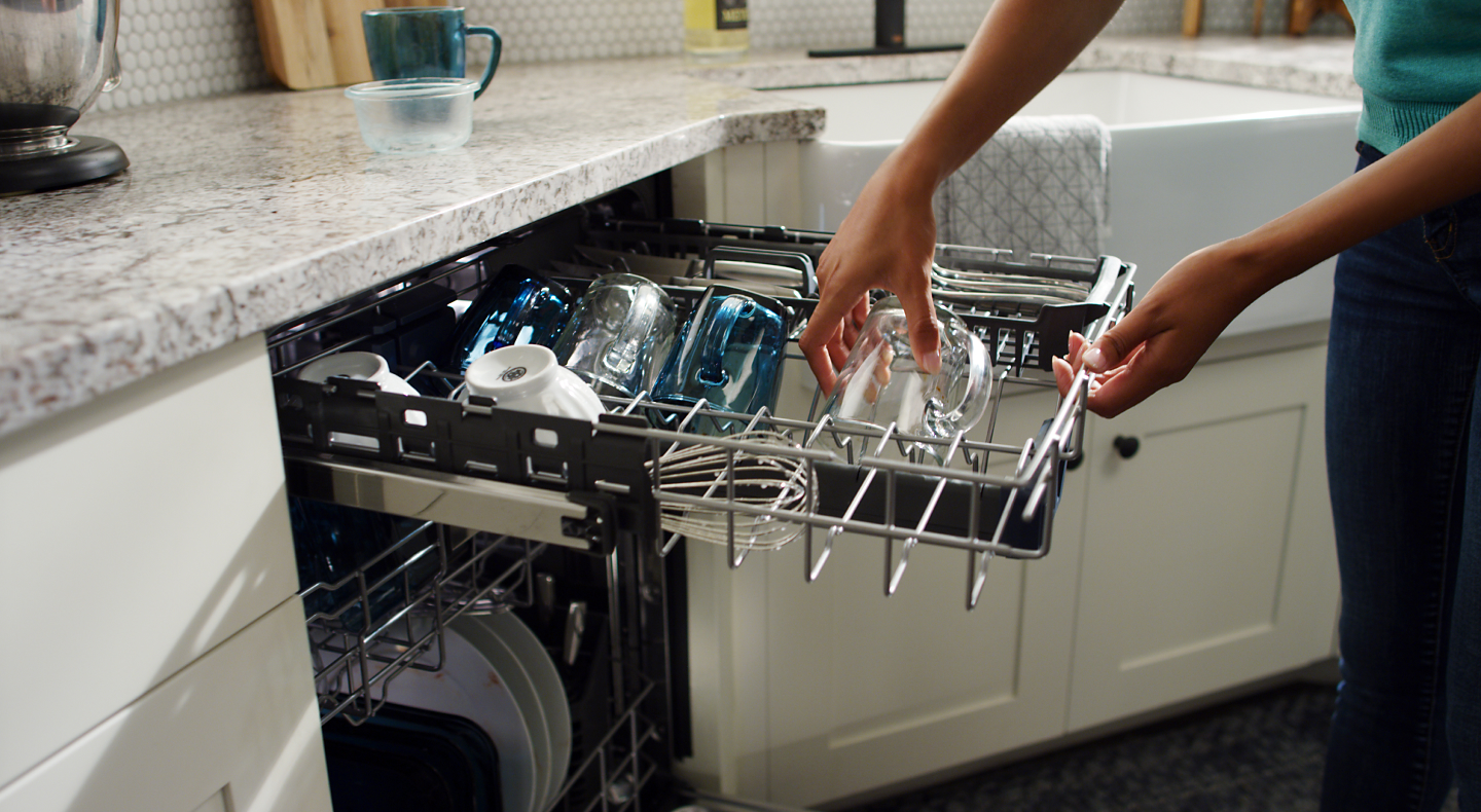 Person loading dishes into a dishwasher top rack