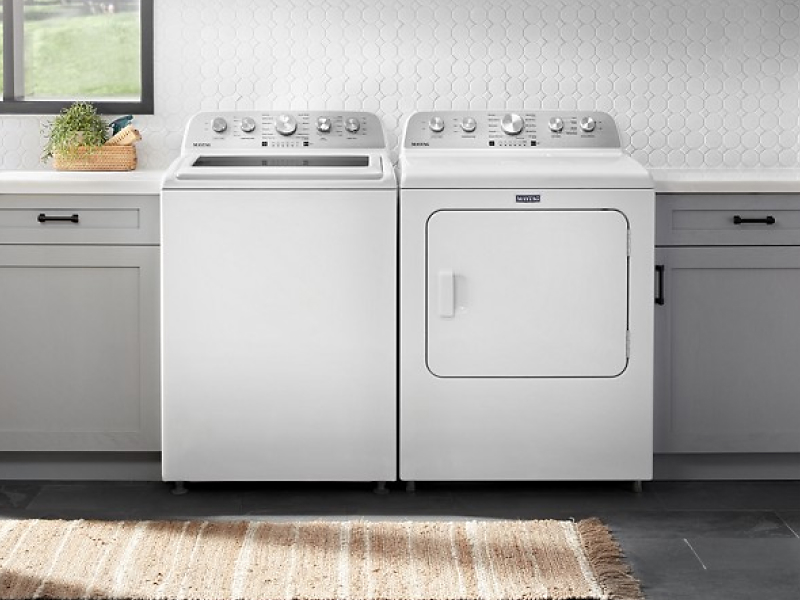 A white top load washer next to white front load dryer in kitchen entryway