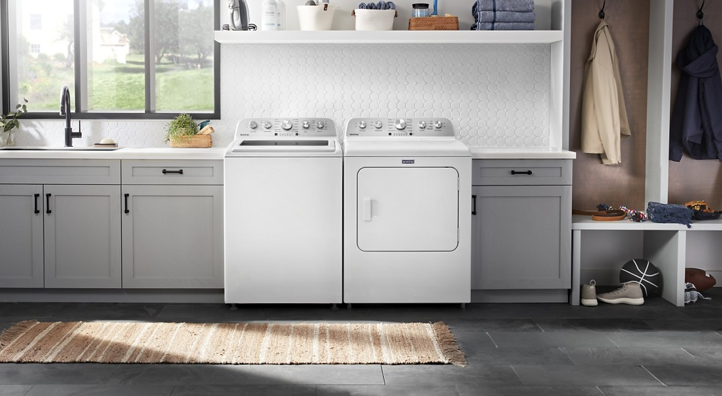A white top load washer next to white front load dryer in kitchen entryway