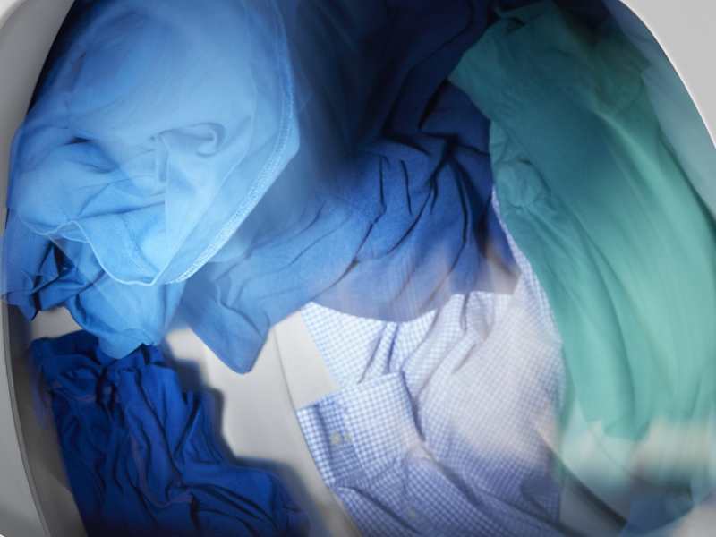 Blue and green colored clothes tumbling in dryer