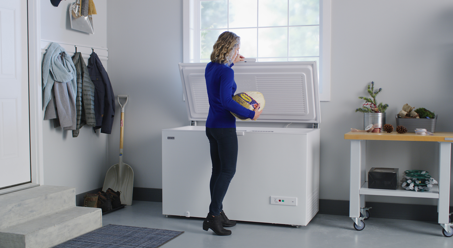 Woman removing a frozen turkey from a Maytag® chest freezer