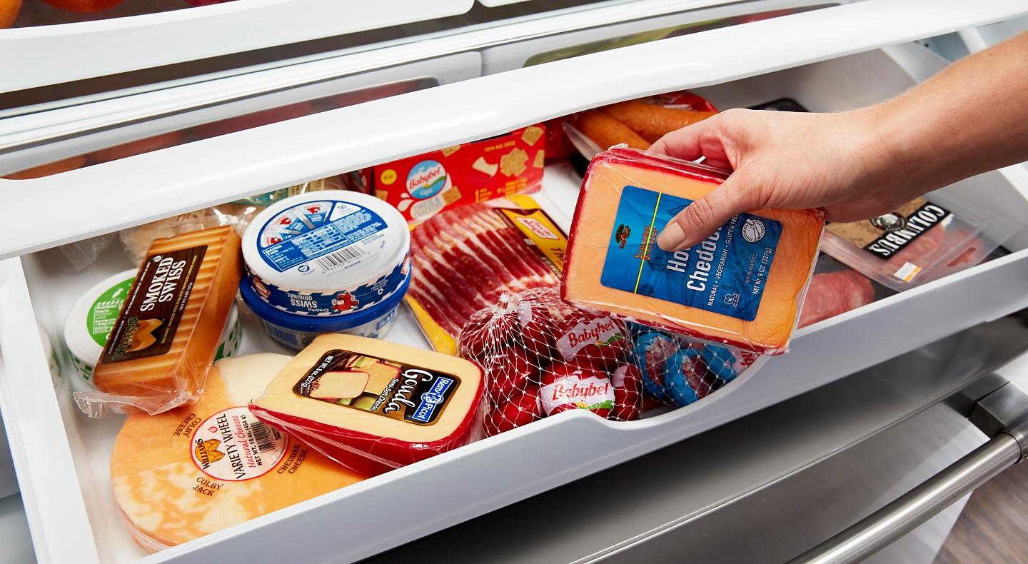 Maytag brand refrigerator’s deli drawer stocked with meats and cheeses