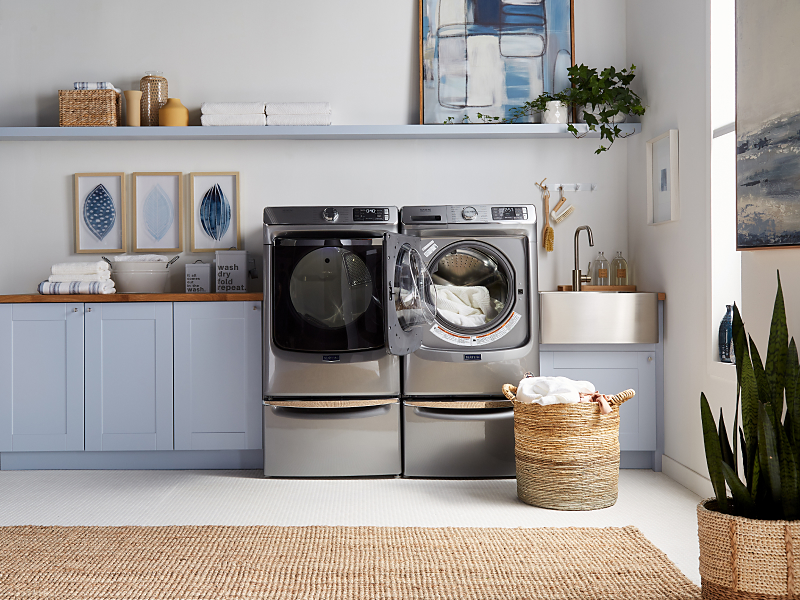 A Maytag® Front Load Washer and Dryer in a rustic laundry room