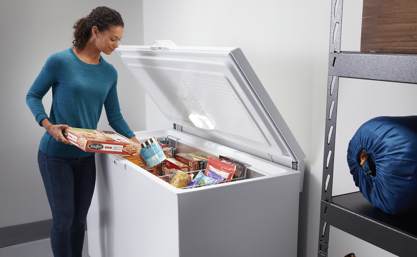Person loading frozen food into chest freezer baskets