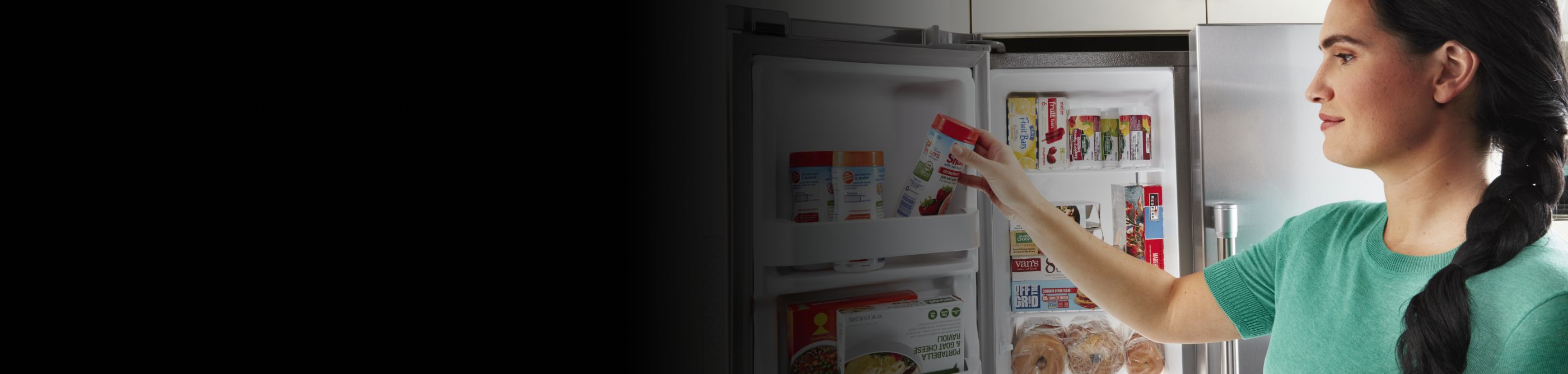 Person removing frozen food from a side-by-side fridge freezer compartment