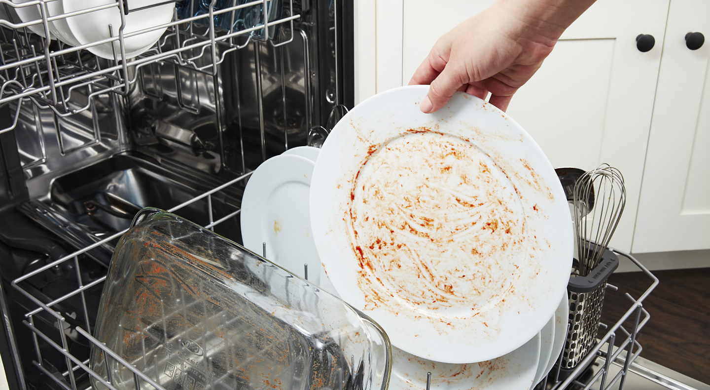 Person loading soiled dishes into a dishwasher