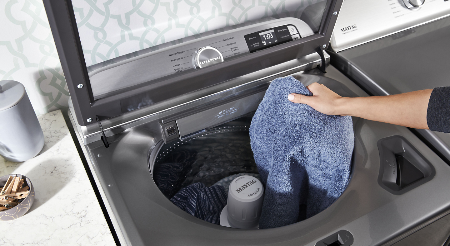 A towel being placed in a Maytag® washer