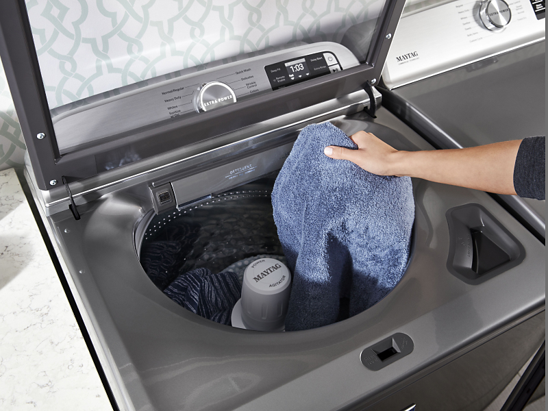 A towel being placed in a Maytag® washer