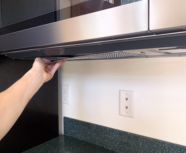 Hand placing filter back onto its position within microwave 