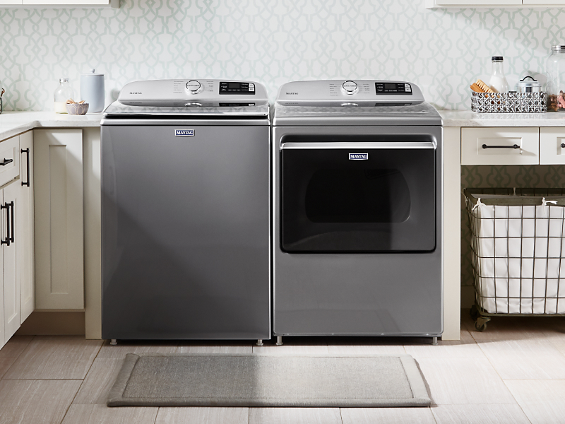 Stainless Maytag® top load washer and front load dryer side by side in a tidy, bright laundry room
