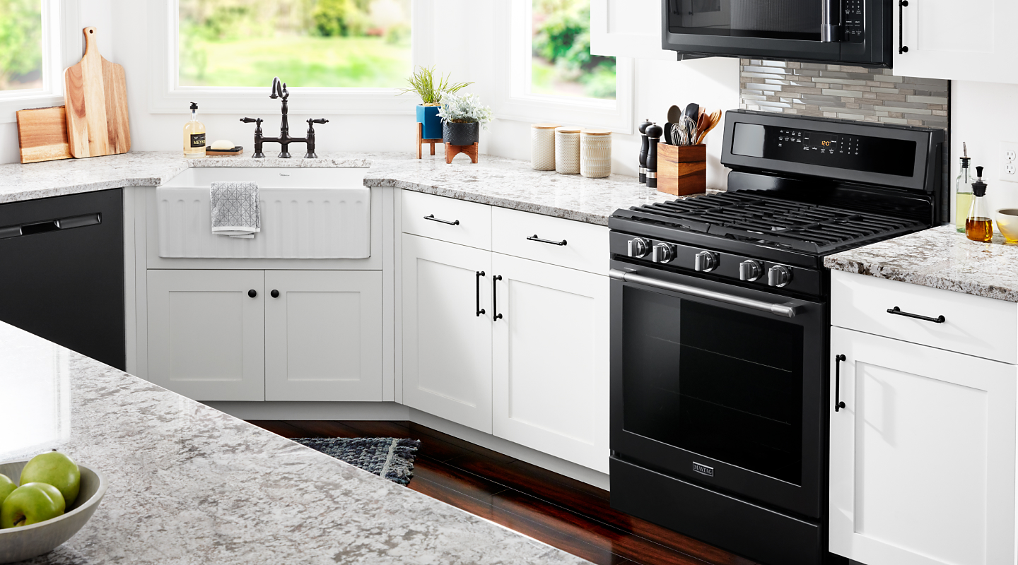 Black Maytag oven set between white cabinets