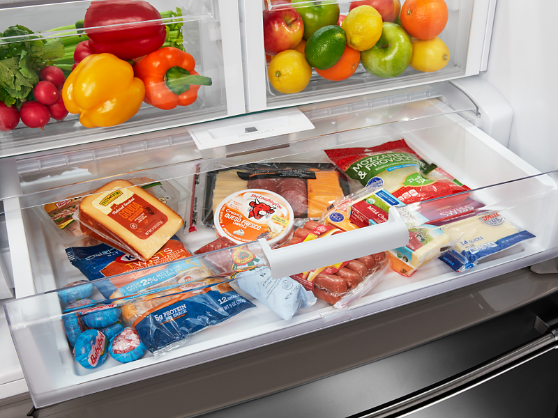 An open deli drawer of a Maytag® refrigerator with fresh food.
