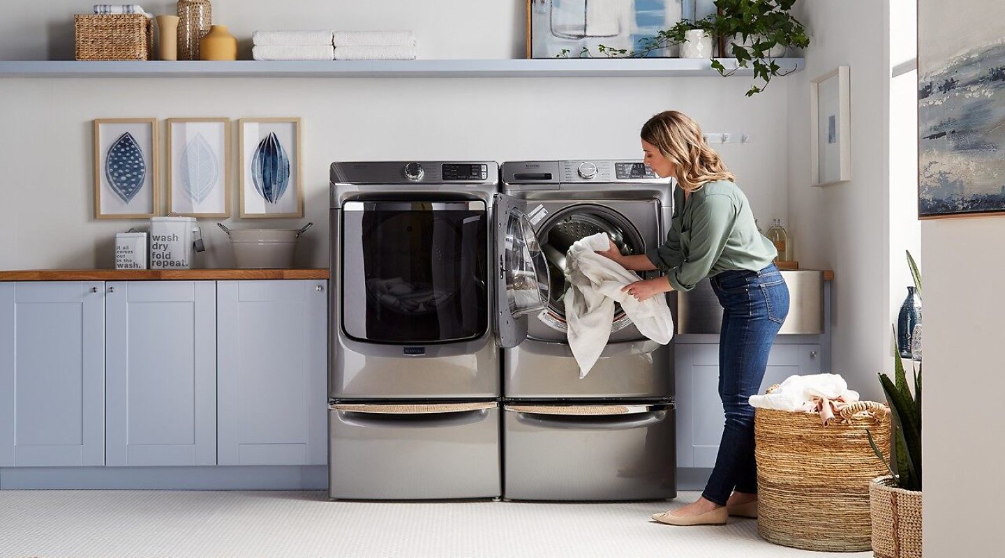 Woman loading a washer and dryer with laundry