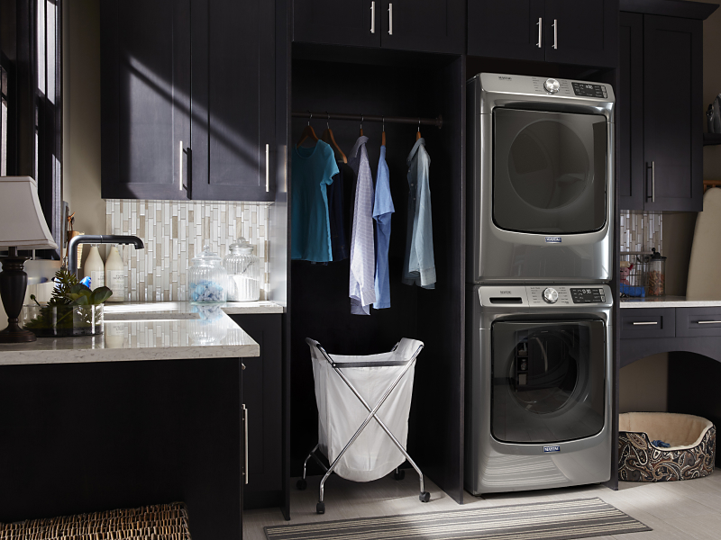 Clothes hanging next to a stacked Maytag® washer and dryer set
