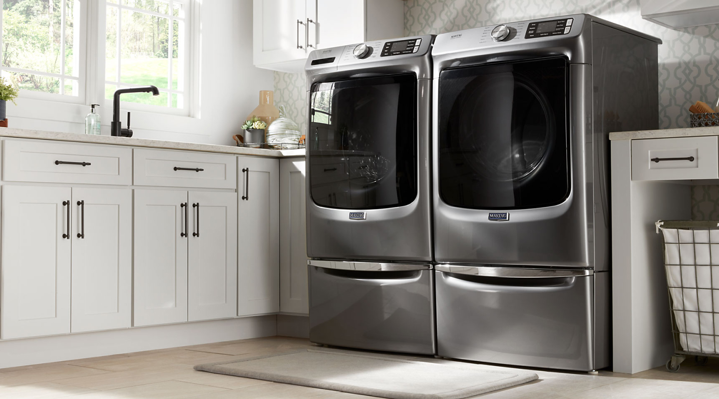 Two front loading Maytag® dryers side by side in a modern kitchen