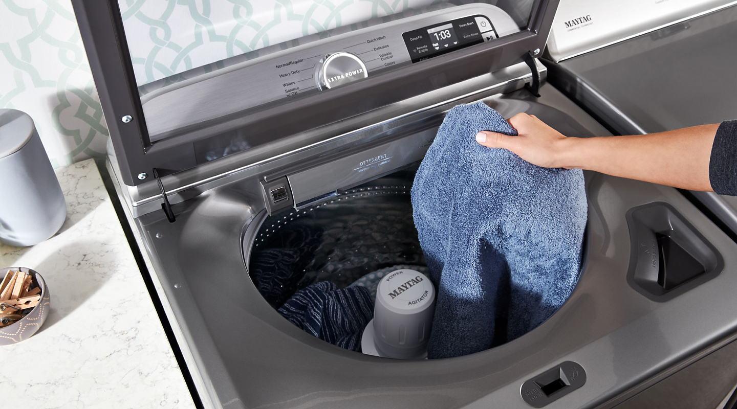 Person loading laundry into a top loading Maytag® washer Person loading laundry into a top loading Maytag® washer