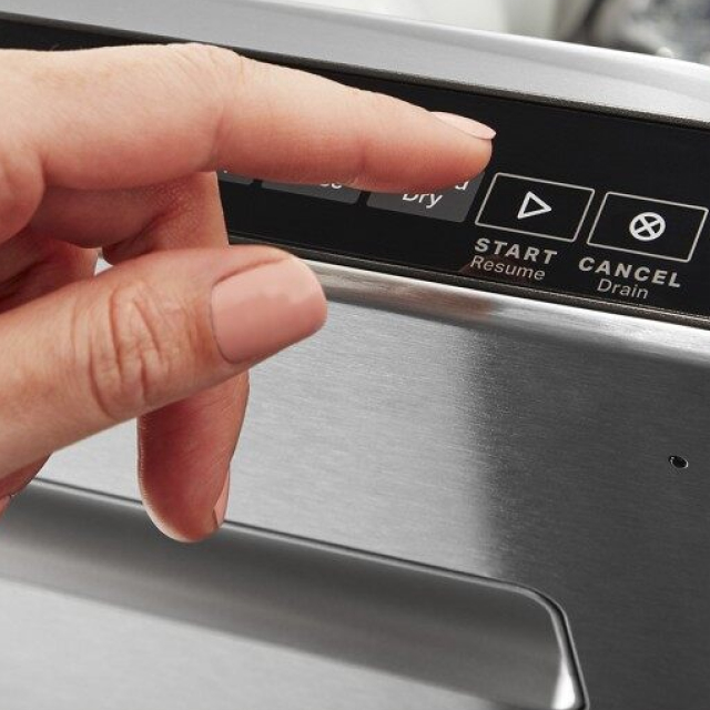 Hand pressing start on a dishwasher control panel