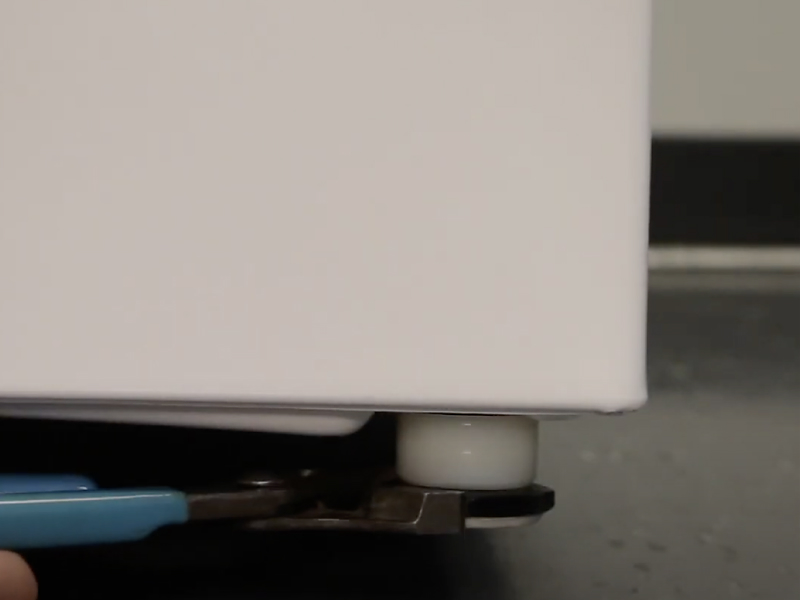 A man adjusting the leveling feet of a Maytag® washing machine. A man adjusting the leveling feet of a Maytag® washing machine.