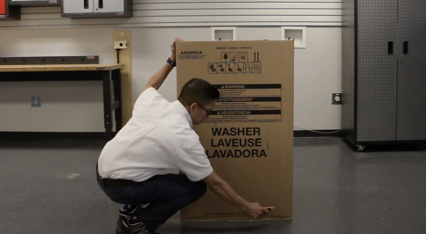 A man unpacking a Maytag® top load washing machine.