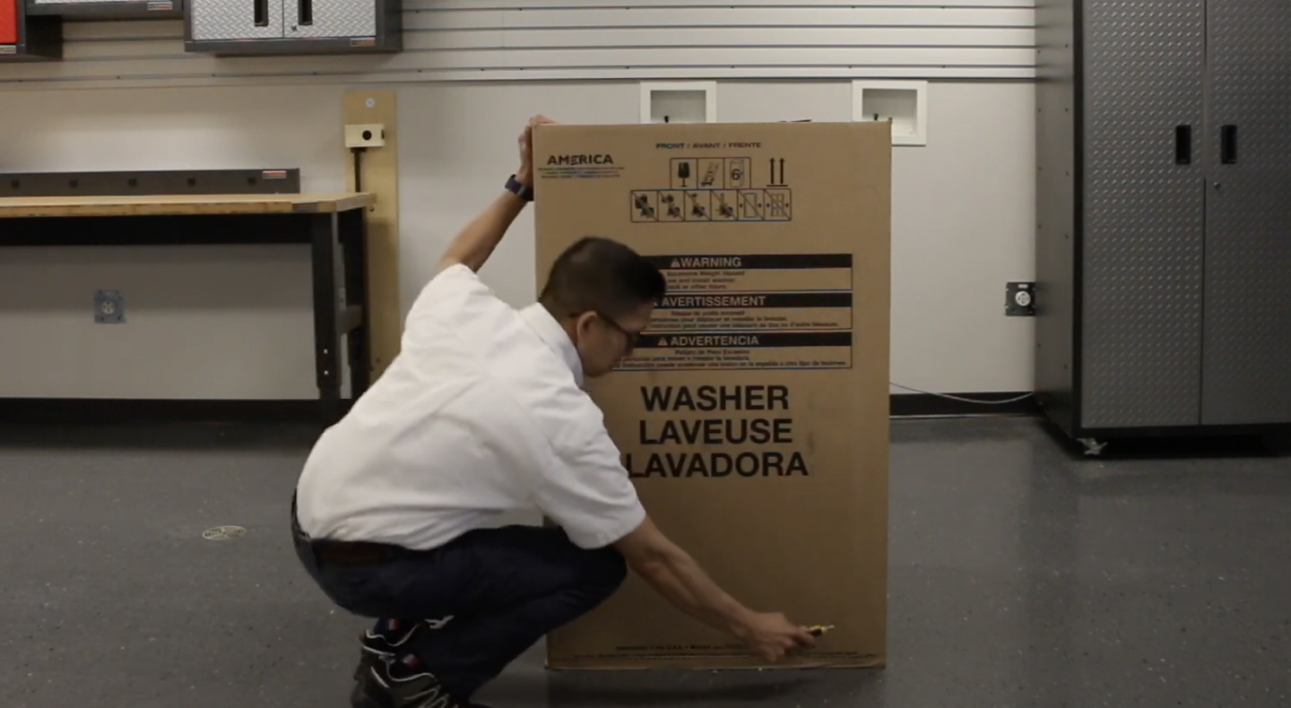 A man unpacking a Maytag® top load washing machine. A man unpacking a Maytag® top load washing machine.