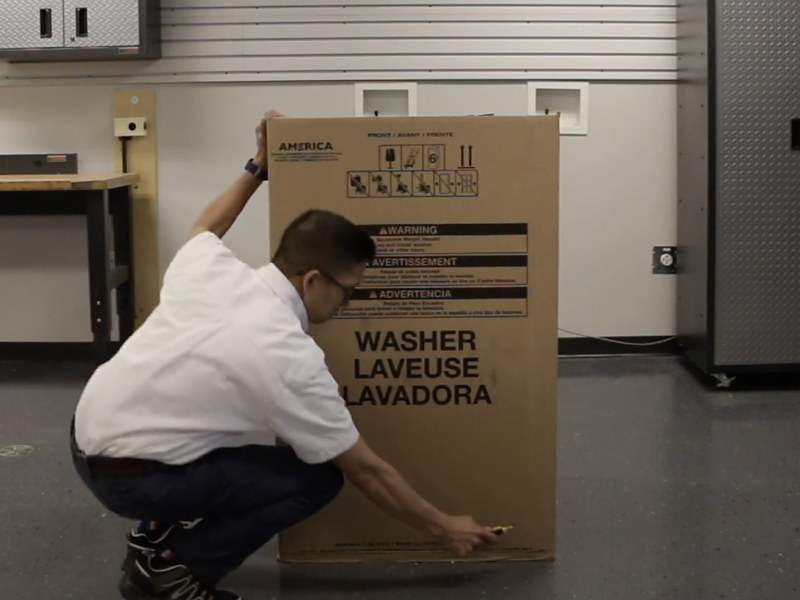 A man unpacking a Maytag® top load washing machine. A man unpacking a Maytag® top load washing machine.