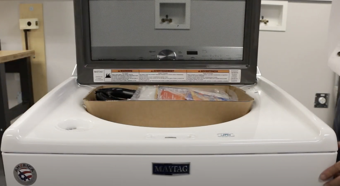 A closeup of a Maytag® top load washing machine with the cardboard packing tray inside. A closeup of a Maytag® top load washing machine with the cardboard packing tray inside.