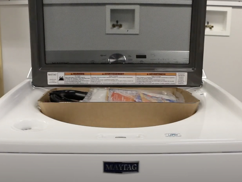 A closeup of a Maytag® top load washing machine with the cardboard packing tray inside. A closeup of a Maytag® top load washing machine with the cardboard packing tray inside.