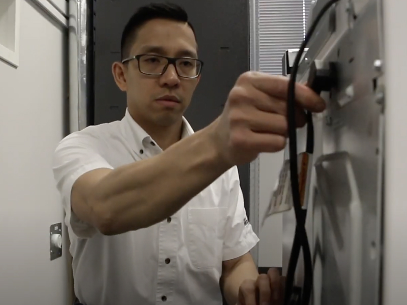A man freeing the power cord from a Maytag® washing machine. A man freeing the power cord from a Maytag® washing machine.