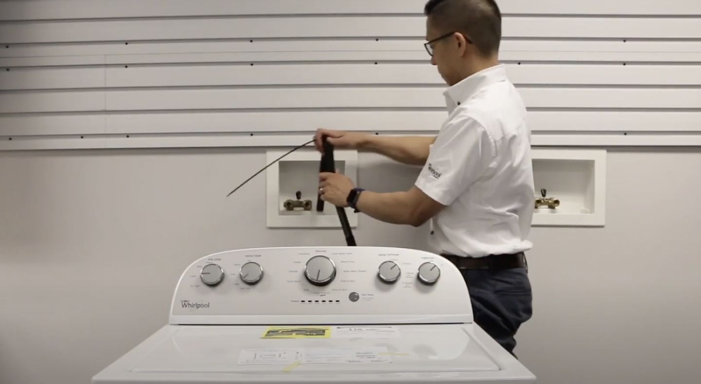 A man placing a drain hose into the standpipe of a Maytag® washing machine. A man placing a drain hose into the standpipe of a Maytag® washing machine.
