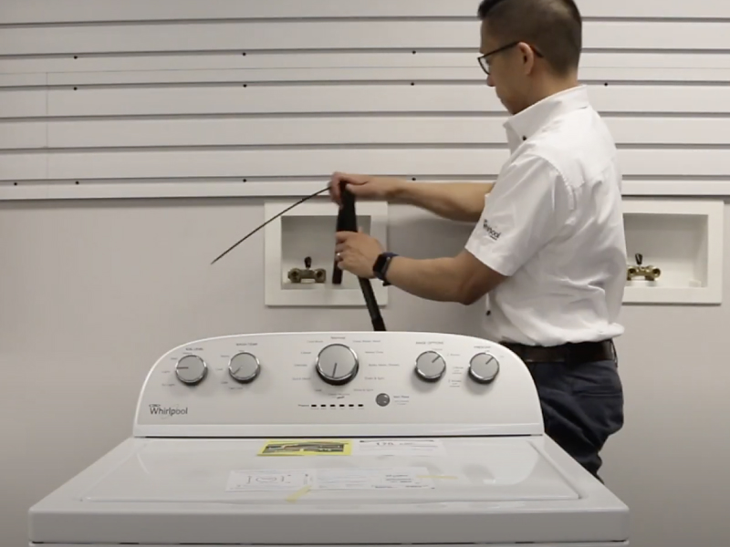 A man placing a drain hose into the standpipe of a Maytag® washing machine. P#: screenshot of video