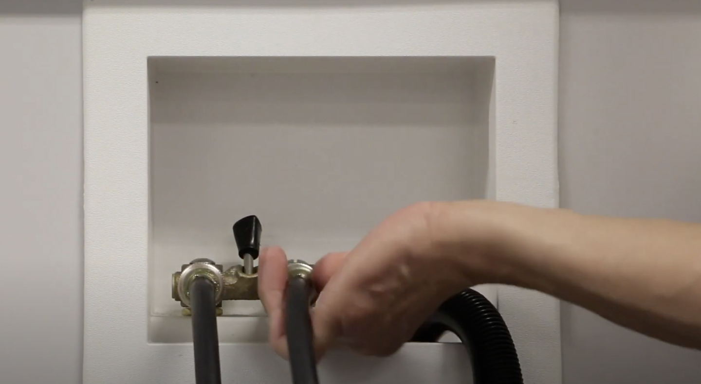 A man connecting the inlet hoses of a Maytag® washing machine to the water faucets. A man connecting the inlet hoses of a Maytag® washing machine to the water faucets.