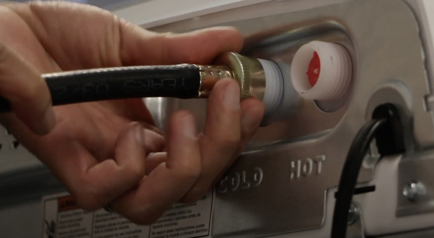 A man connecting inlet hoses to a Maytag® washing machine. A man connecting inlet hoses to a Maytag® washing machine.