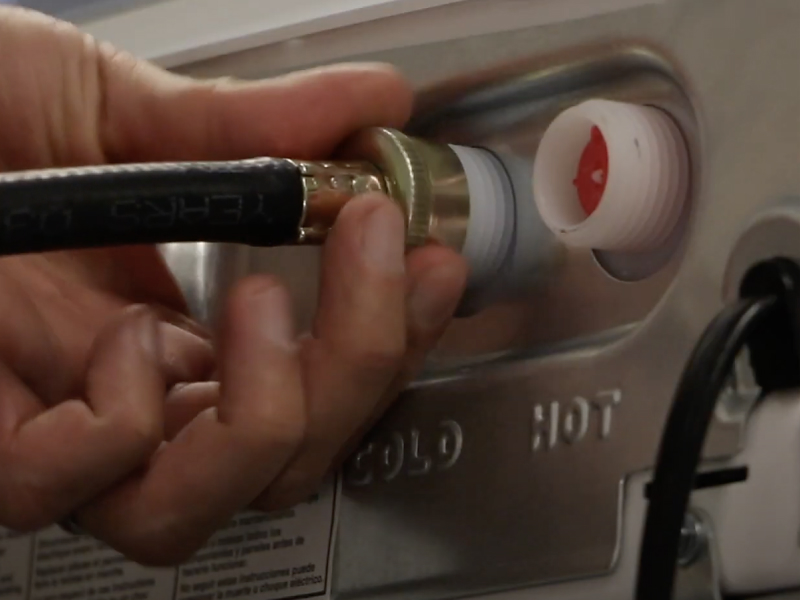 A man connecting inlet hoses to a Maytag® washing machine. A man connecting inlet hoses to a Maytag® washing machine.