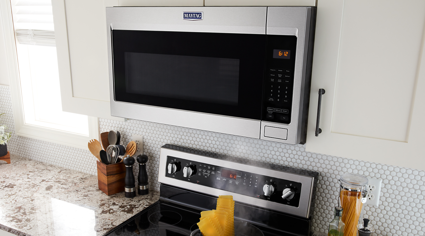 A Maytag® over-the-range microwave with a boiling pot on the stove.