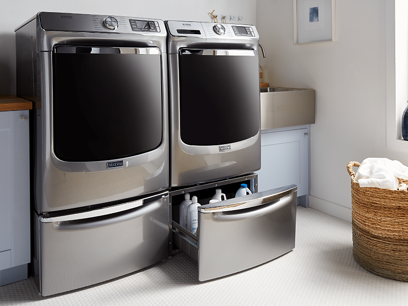 Maytag® washer and dryer on pedestals in a modern laundry room