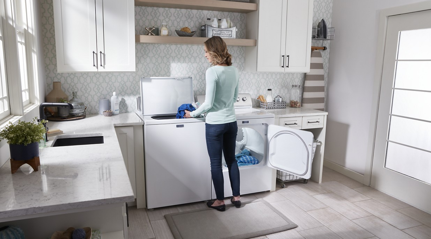 Person doing laundry with a white Maytag® laundry set